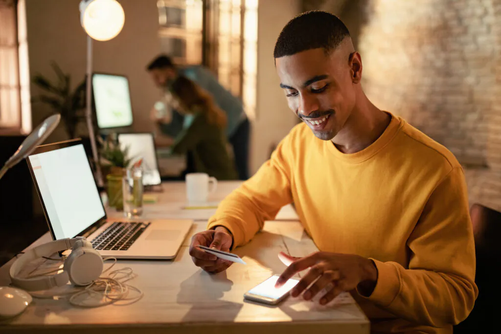Happy black businessman m banking while working late in the offi